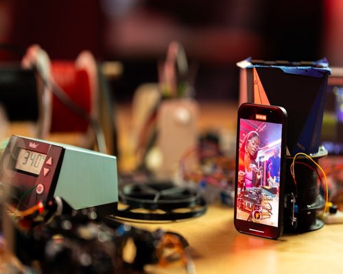 Central smartphone showing fictional Infinity Crown Workshop game
